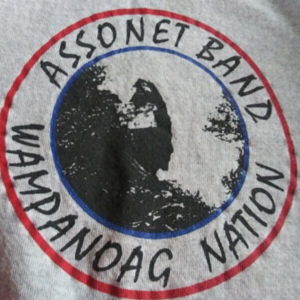 http://The%20Assonet%20Band%20of%20Wampanoags%20tribal%20seal,%20featuring%20a%20black%20and%20white%20silhouette%20image%20of%20a%20person%20in%20traditional%20regalia%20peering%20out%20from%20the%20treeline,%20surrounded%20by%20a%20blue%20circle%20with%20an%20outer%20red%20ring,%20and%20the%20words%20“Assonet%20Band”%20and%20“Wampanoag%20Nation”%20written%20in%20black%20text%20between%20them.