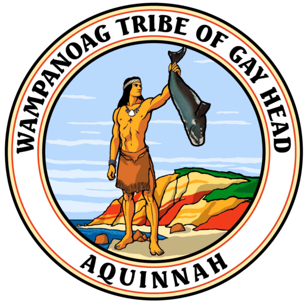http://The%20Wampanoag%20Tribe%20of%20Gay%20Head%20(Aquinnah)%20tribal%20seal,%20featuring%20a%20man%20in%20traditional%20regalia%20holding%20a%20whale%20up%20in%20the%20air%20with%20one%20hand,%20standing%20on%20a%20colorful,%20rocky%20coastline,%20with%20a%20blue%20sky%20and%20ocean%20in%20the%20background,%20encircled%20by%20the%20words%20“Wampanoag%20Tribe%20of%20Gay%20Head”%20above,%20and%20“Aquinnah”%20below,%20within%20red%20and%20then%20black%20rings.